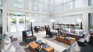 A spacious living area with a modern design, featuring leather sofas, wooden coffee tables, and a large window with a view of the outdoors. - DoubleTree by Hilton Hotel Chattanooga Downtown (Chattanooga)