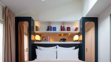 A hotel room with a bed, a built-in bookshelf, and a skylight.