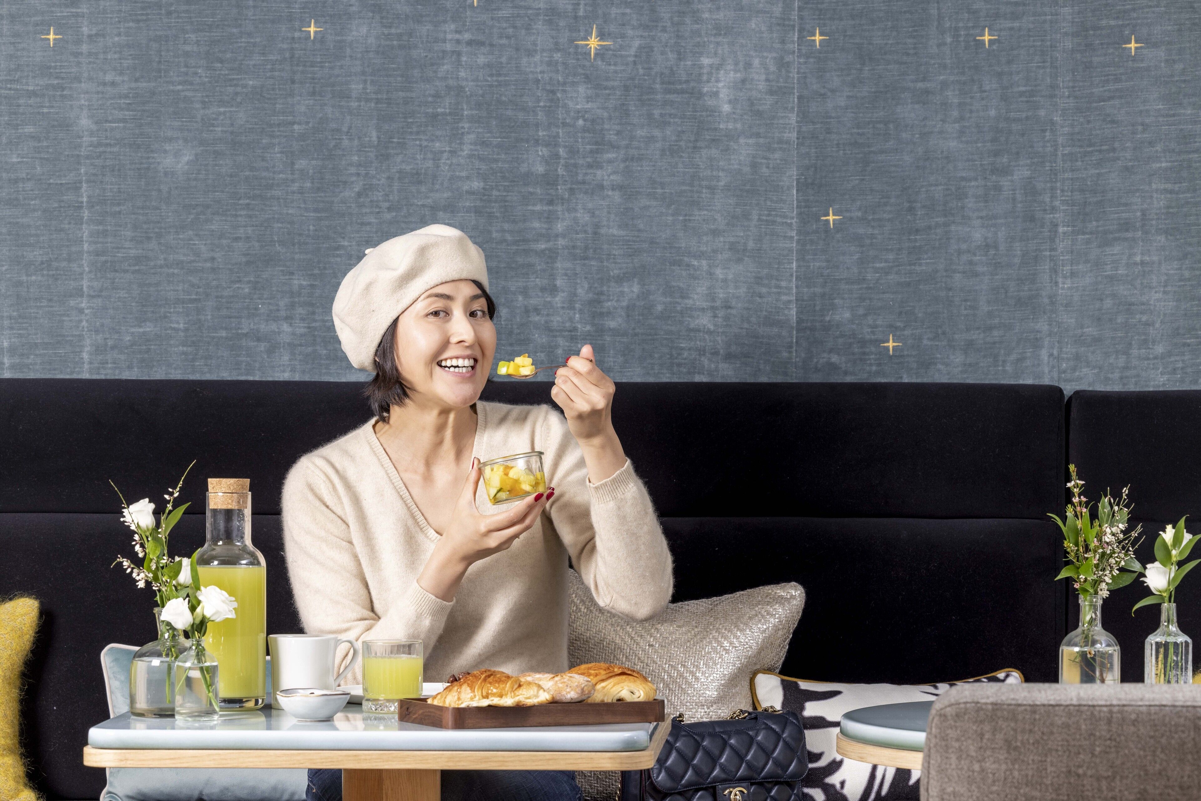 A person sitting on a black sofa with a tray of food and drinks in front of them.