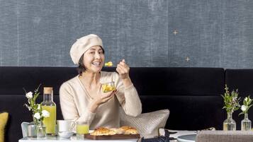 A person sitting on a black sofa with a tray of food and drinks in front of them.