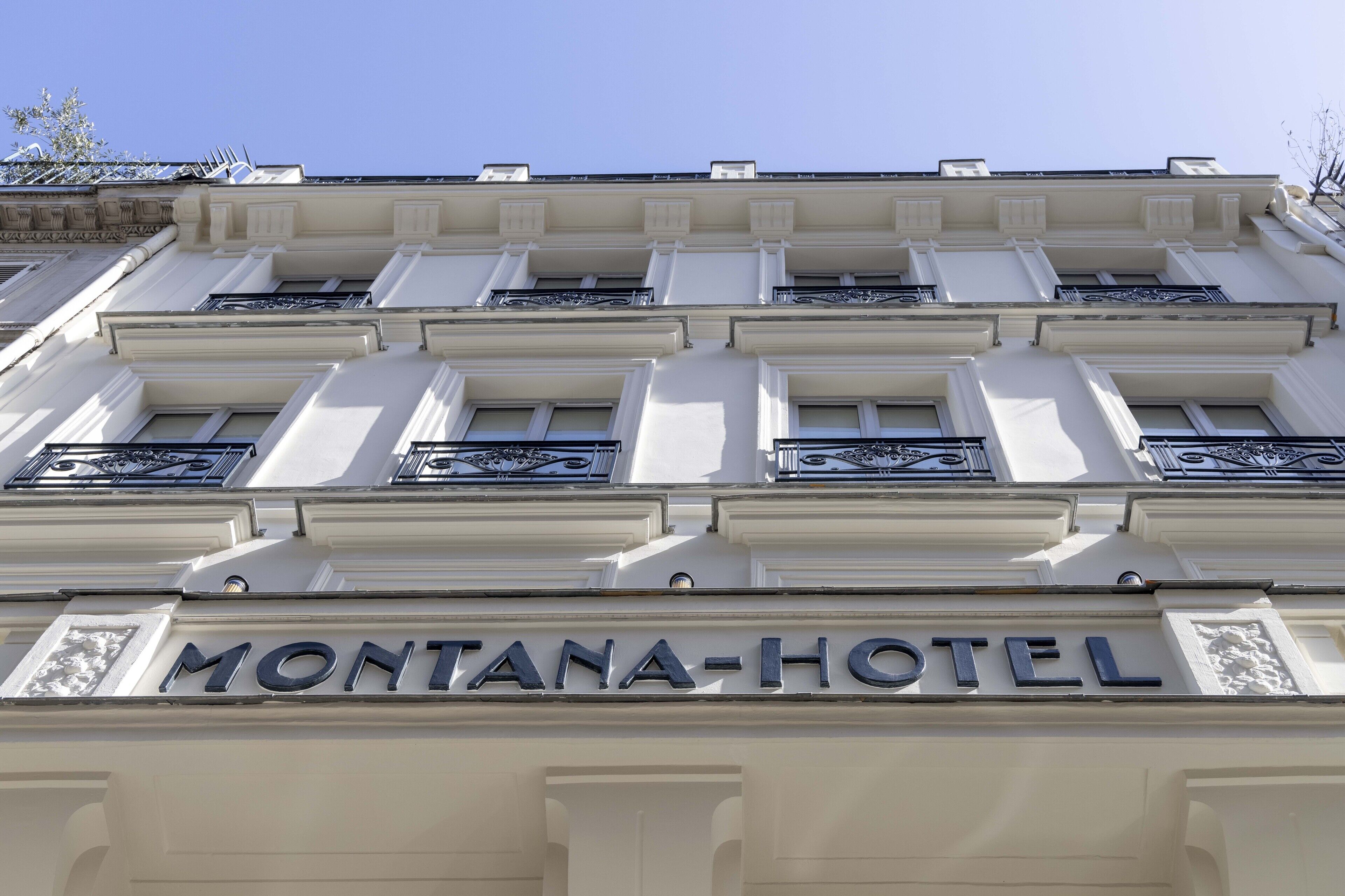 Exterior del Montana-Hotel con un estilo arquitectónico clásico, que destaca una entrada imponente y barandillas decorativas.