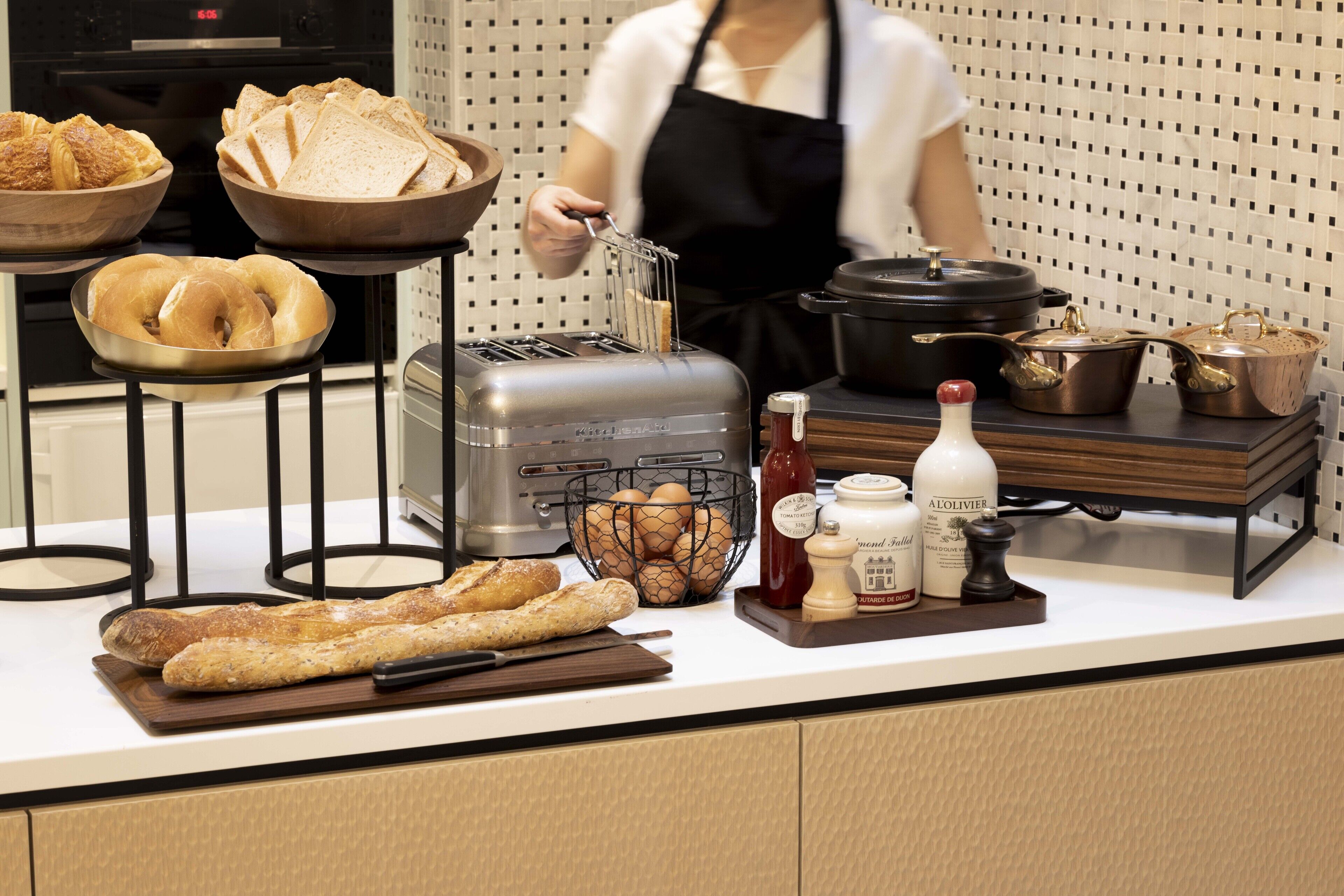 A kitchen counter with various food items and kitchenware, including bread, eggs, a toaster, and a pot.