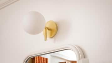 A wall-mounted light fixture with a spherical shade and a brass pull chain.