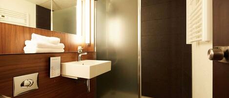 A modern bathroom with a glass shower enclosure, a white sink, and a wooden vanity.