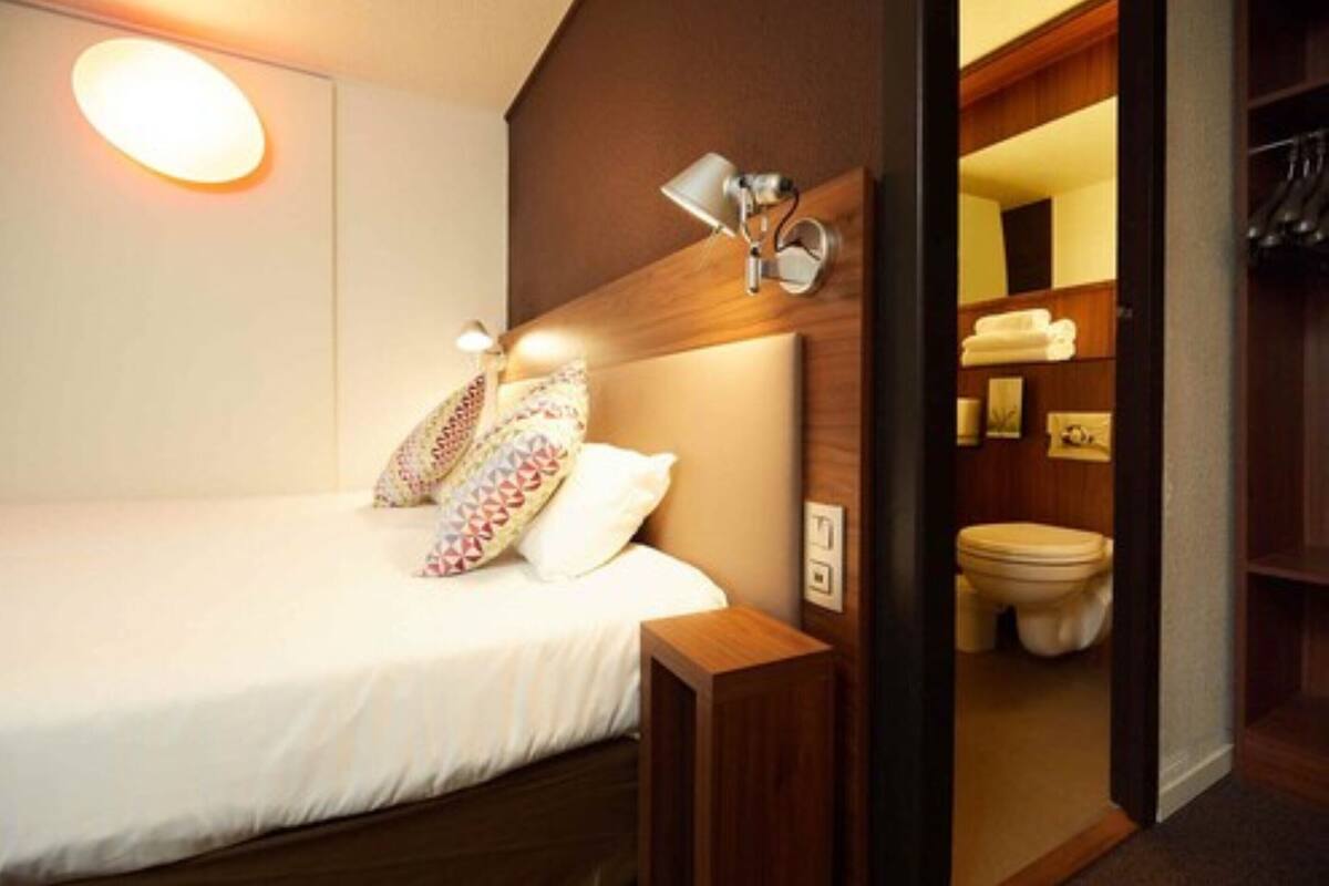 Ein Hotelzimmer mit Bett, Nachttischlampe und Blick ins Badezimmer.