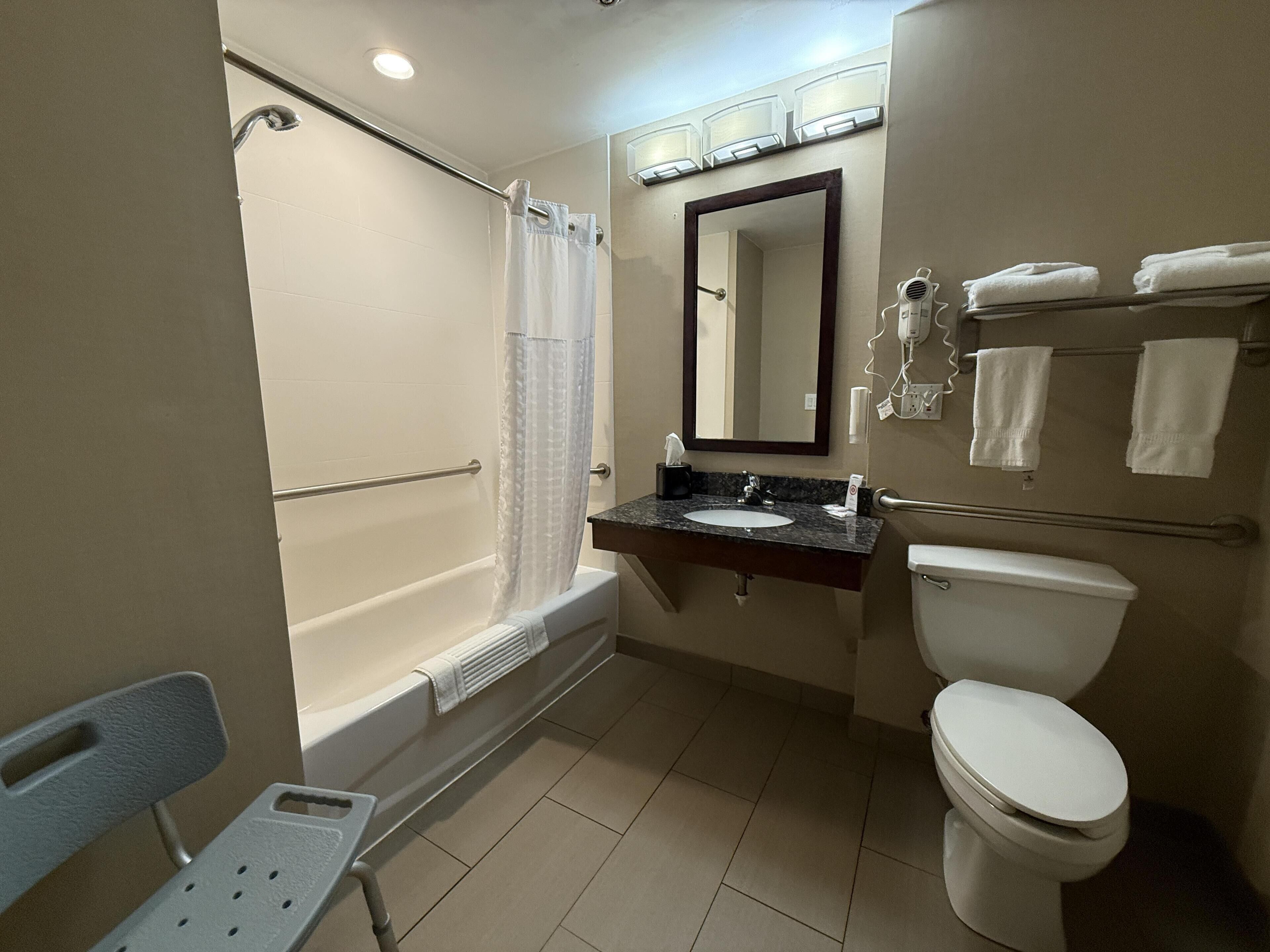 A standard hotel bathroom with a bathtub, toilet, sink, and a mirror.