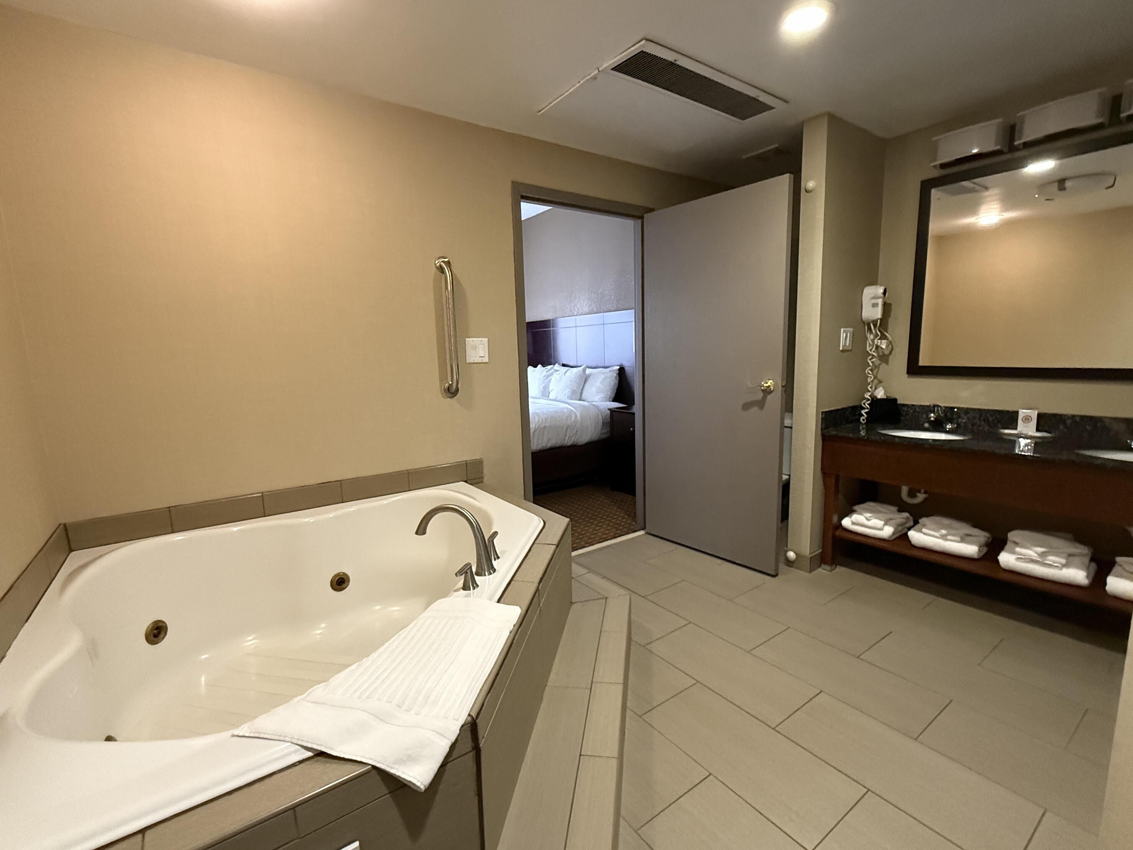 Uma casa de banho moderna com uma banheira grande, zona de duche separada e toucador com espelho e porta-toalhas.