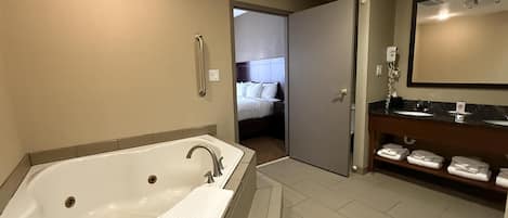 A modern bathroom with a large bathtub, a separate shower area, and a vanity with a mirror and towel rack.