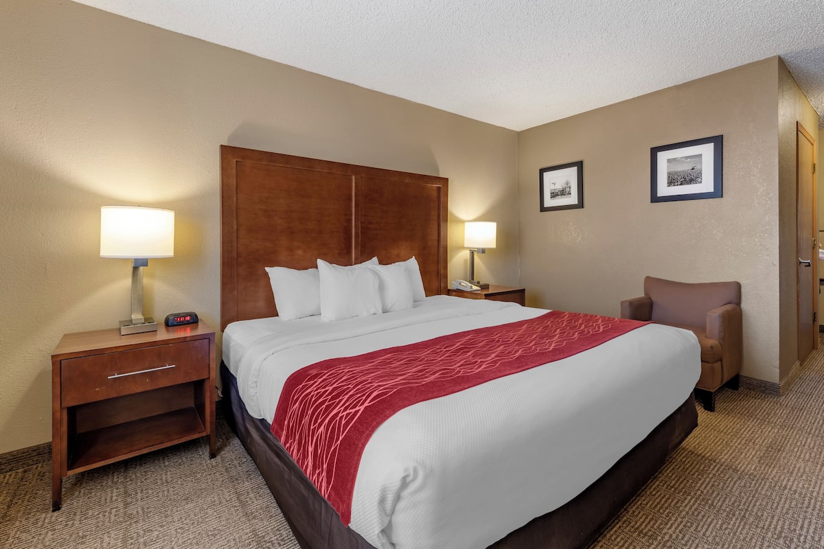 A hotel room with a large bed, two bedside tables, a chair, and two framed pictures on the wall.