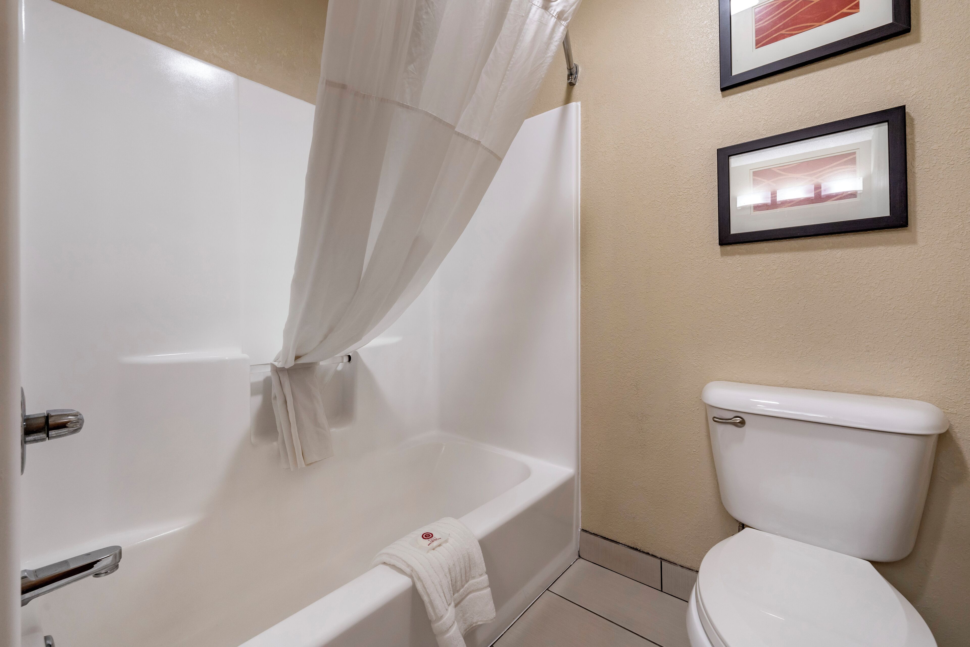 Een badkamer met een badkuip, toilet en twee foto's in lijsten aan de muur.