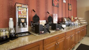 A hotel kitchen with waffle makers, a coffee machine, and a buffet area. - Quality Inn Brooklyn Center (Brooklyn Center)