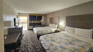 A hotel room with two beds, a desk, a chair, a TV, and a balcony with curtains.