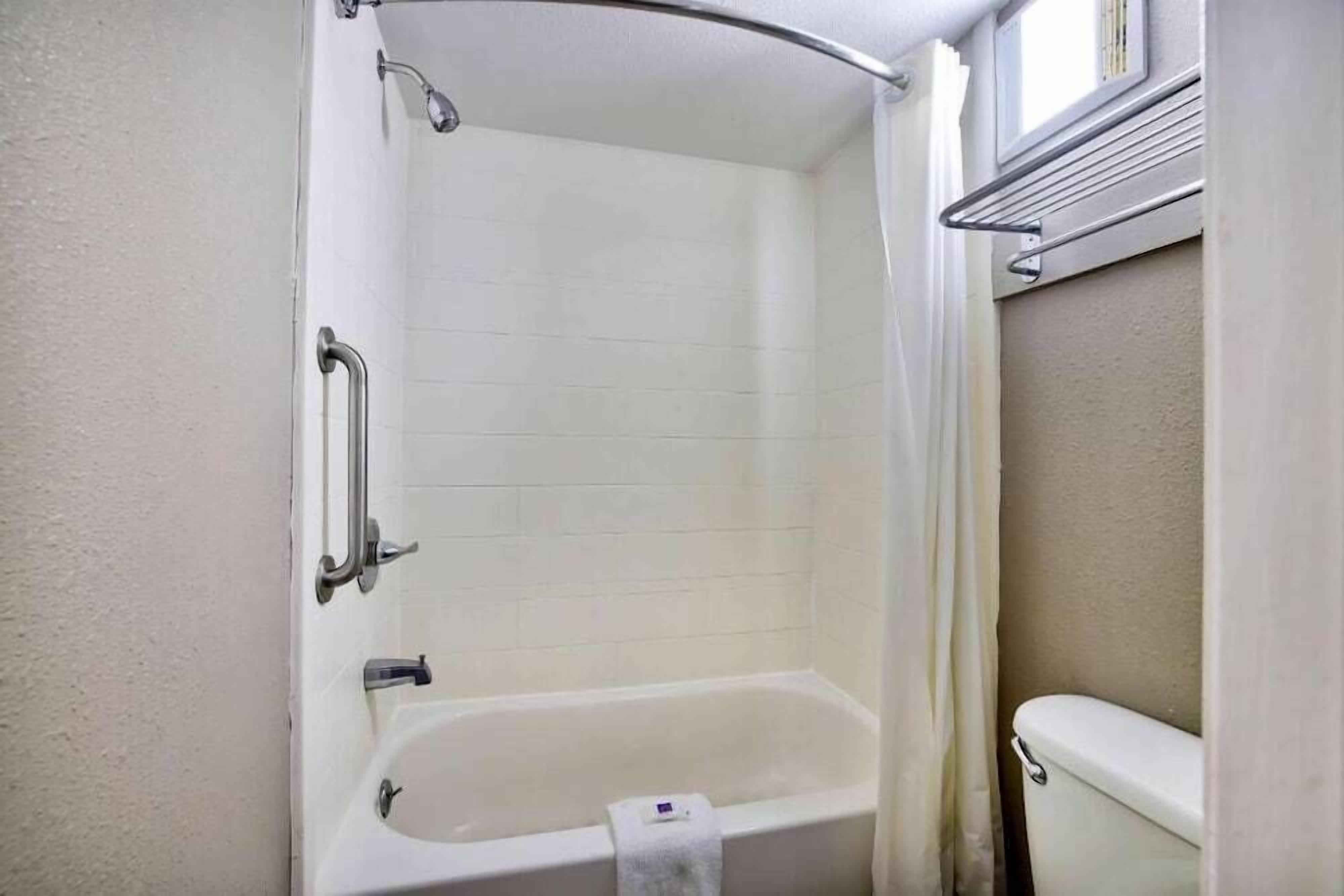 Un baño con bañera, inodoro y cortina de ducha.
