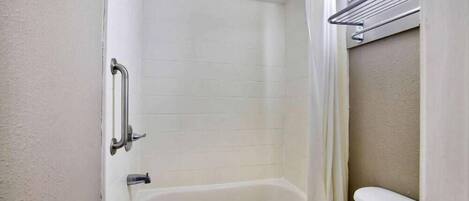 Un baño con bañera, inodoro y cortina de ducha.