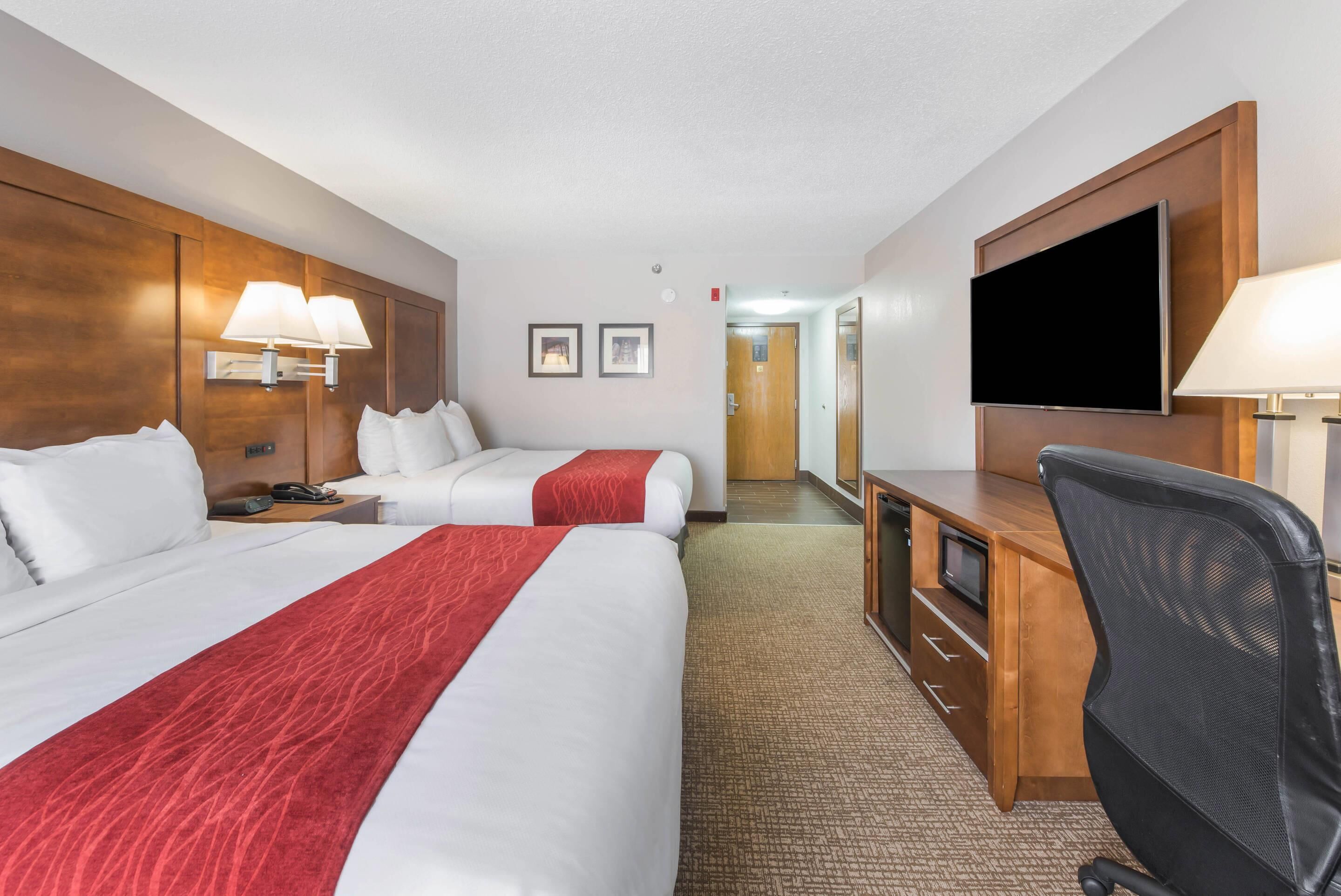 Hotelkamer met twee bedden, een bureau, een stoel, een flatscreen televisie en een lamp.