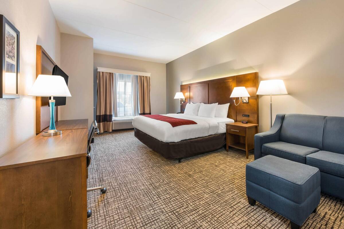 Une chambre d’hôtel avec un lit, un bureau, une chaise et un canapé.
