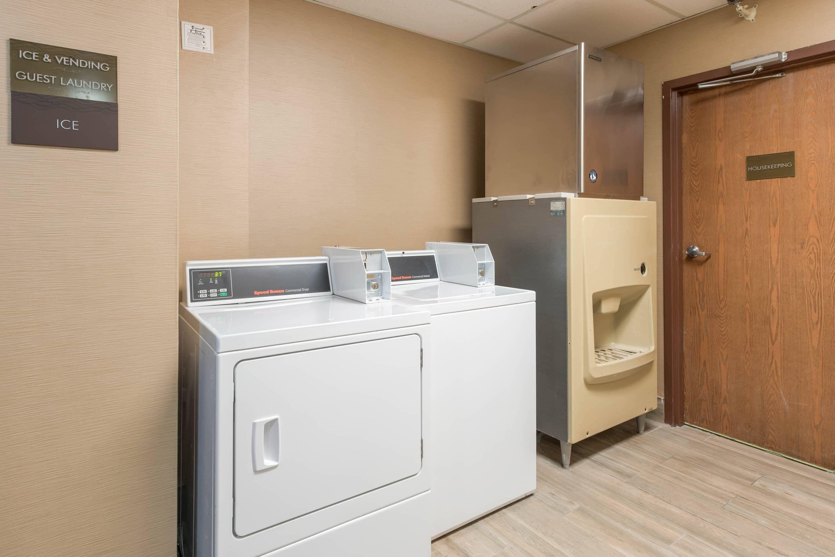 Une chambre d’hôtel équipée d’un lave-linge, d’un réfrigérateur et d’une porte permettant l’accès au service de nettoyage.