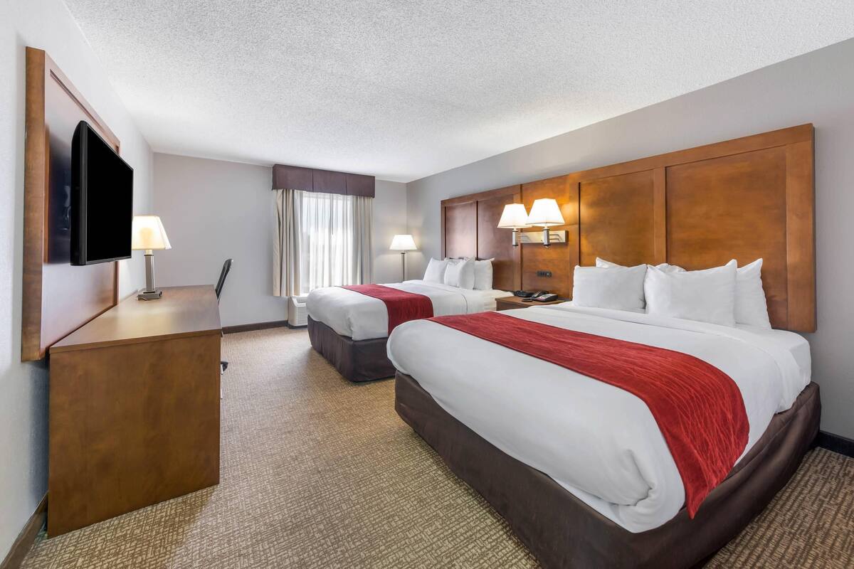 Une chambre d’hôtel avec deux lits, un bureau, une télévision et deux lampes de chevet.