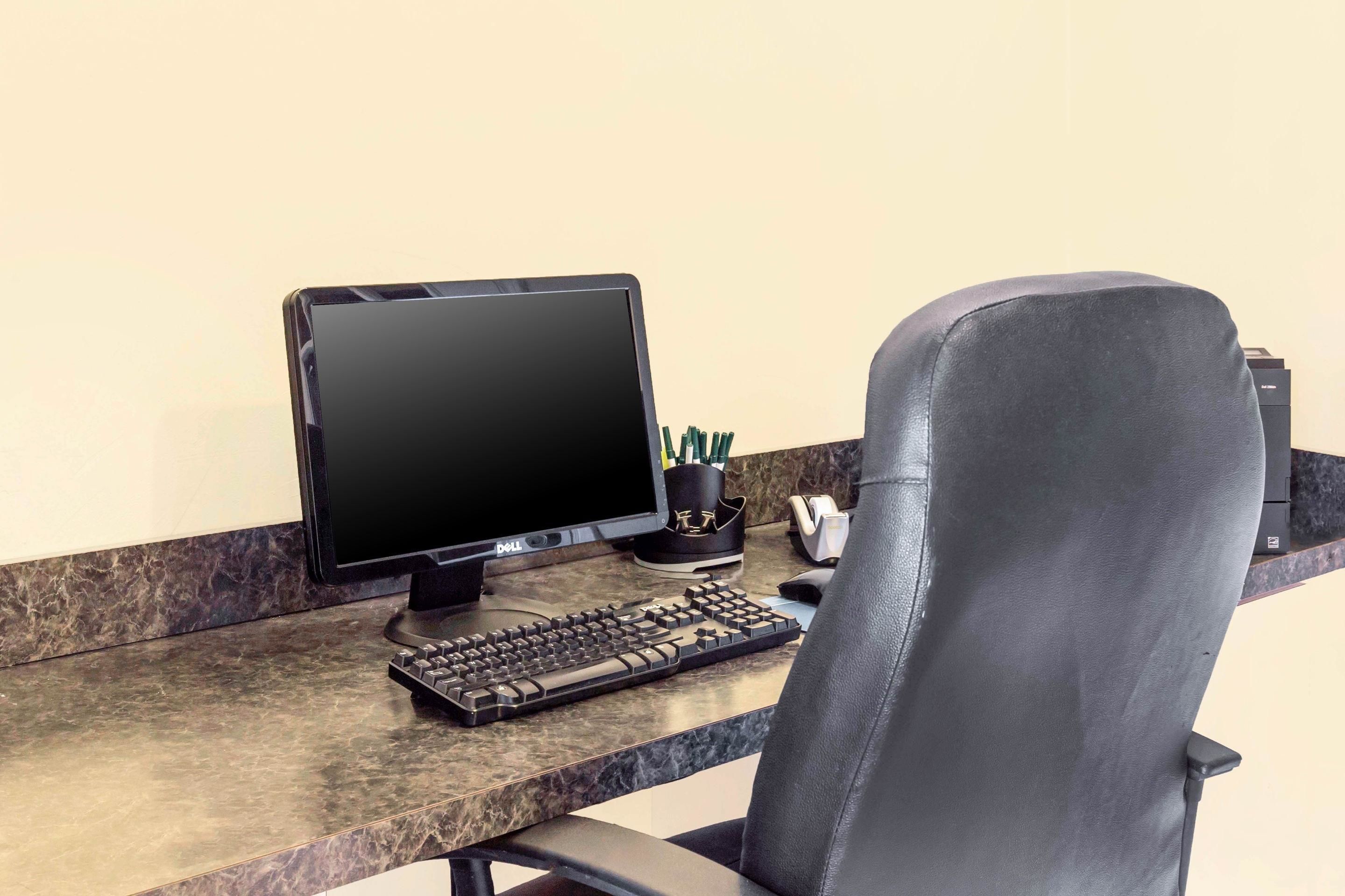 A desk with a computer, keyboard, and chair.