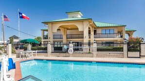 Un hôtel doté d’une piscine, d’un patio couvert et d’un bâtiment à deux étages avec des balcons.