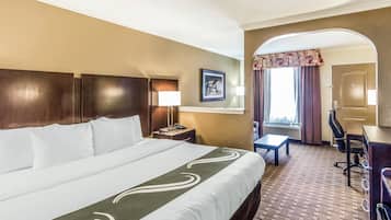 Une chambre d’hôtel avec un grand lit, un bureau, une chaise, une lampe et un tableau au mur.