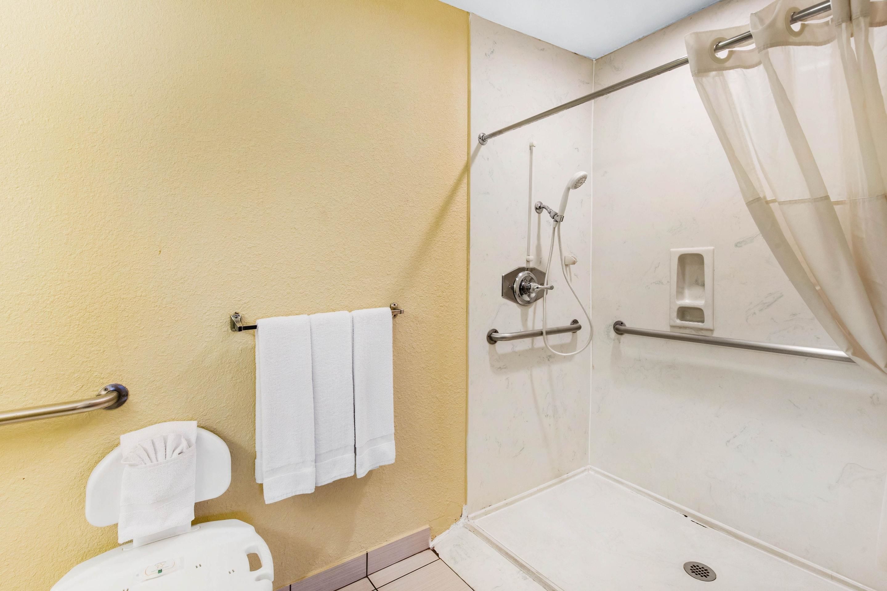 Une salle de bain comprenant des toilettes, une douche avec une porte en verre et un porte-serviettes.