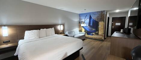 A modern hotel room with a large bed, a desk, a chair, and a wall-mounted TV.