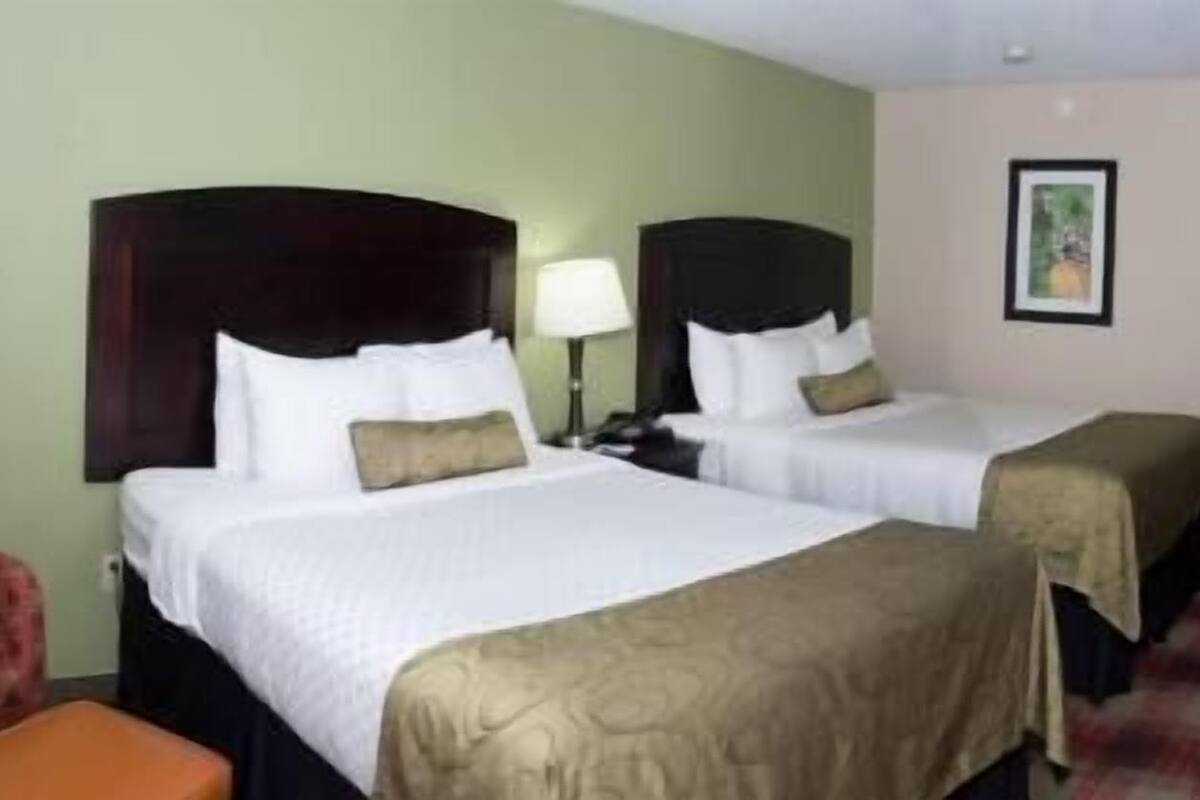 A hotel room with two beds, a chair, and a desk.