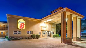 Un hotel Super 8 con fachada de ladrillo, un cartel iluminado grande y una zona de entrada cubierta.