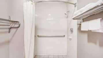 A bathroom with a shower, grab bars, a towel rack, and a toilet paper holder.