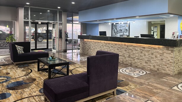 Un hall d’entrée avec un comptoir de réception, un espace salon et une porte d’entrée en verre.