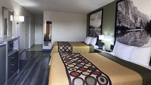 Une chambre d’hôtel avec deux lits, un bureau et un miroir. Il y a un tableau au mur et une fenêtre avec des rideaux.