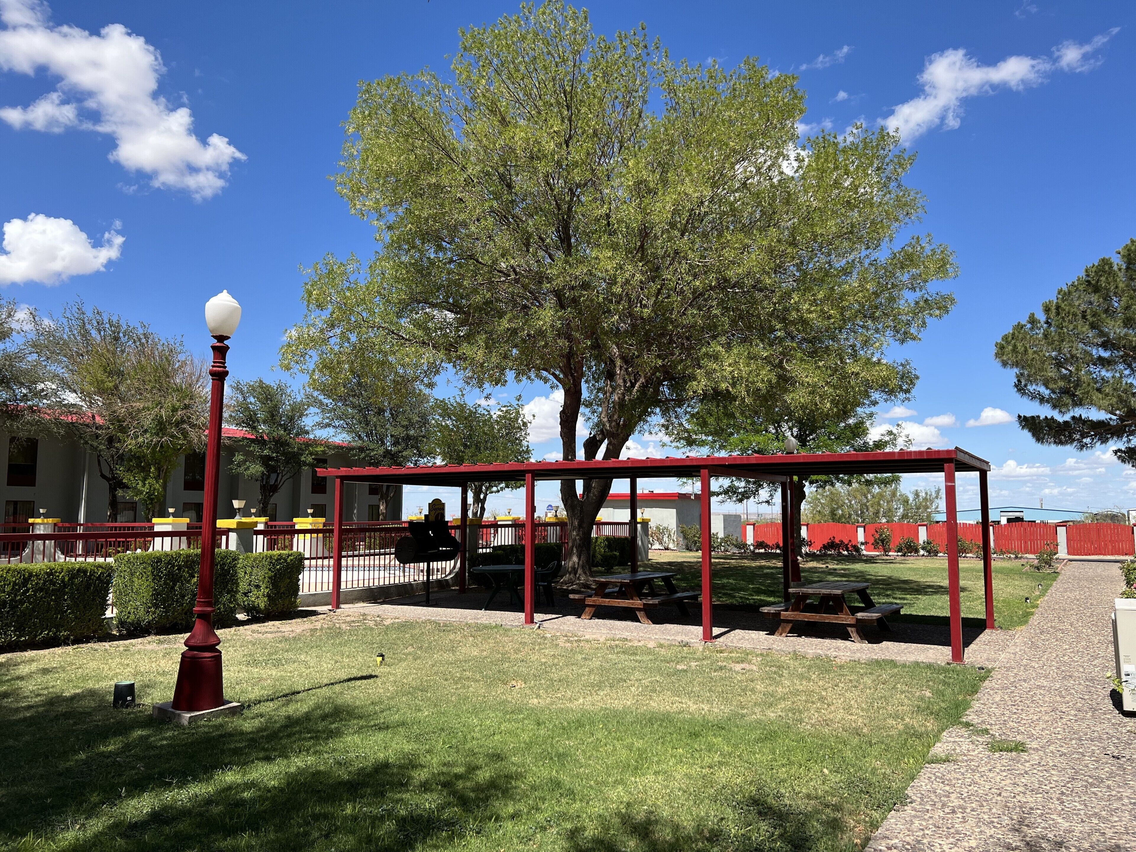 A park with picnic tables, a red gazebo, and a street lamp.