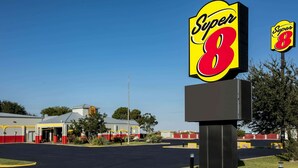 Un motel de type Super 8, avec une grande enseigne, un parking et un bâtiment à la façade rouge et blanche.