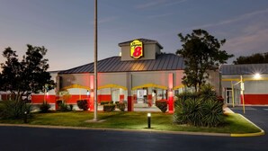 Un hôtel Super 8 avec une façade rouge et blanche, une enseigne «Super 8» bien visible et un parking où sont garées quelques voitures.