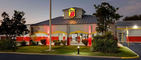 A Super 8 hotel with a red and white facade, a prominent 'Super 8' sign, and a parking lot with a few cars.