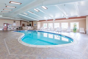 An indoor swimming pool with a tiled floor, a reception desk, and lounge chairs. - Quality Inn & Suites University (Laramie)