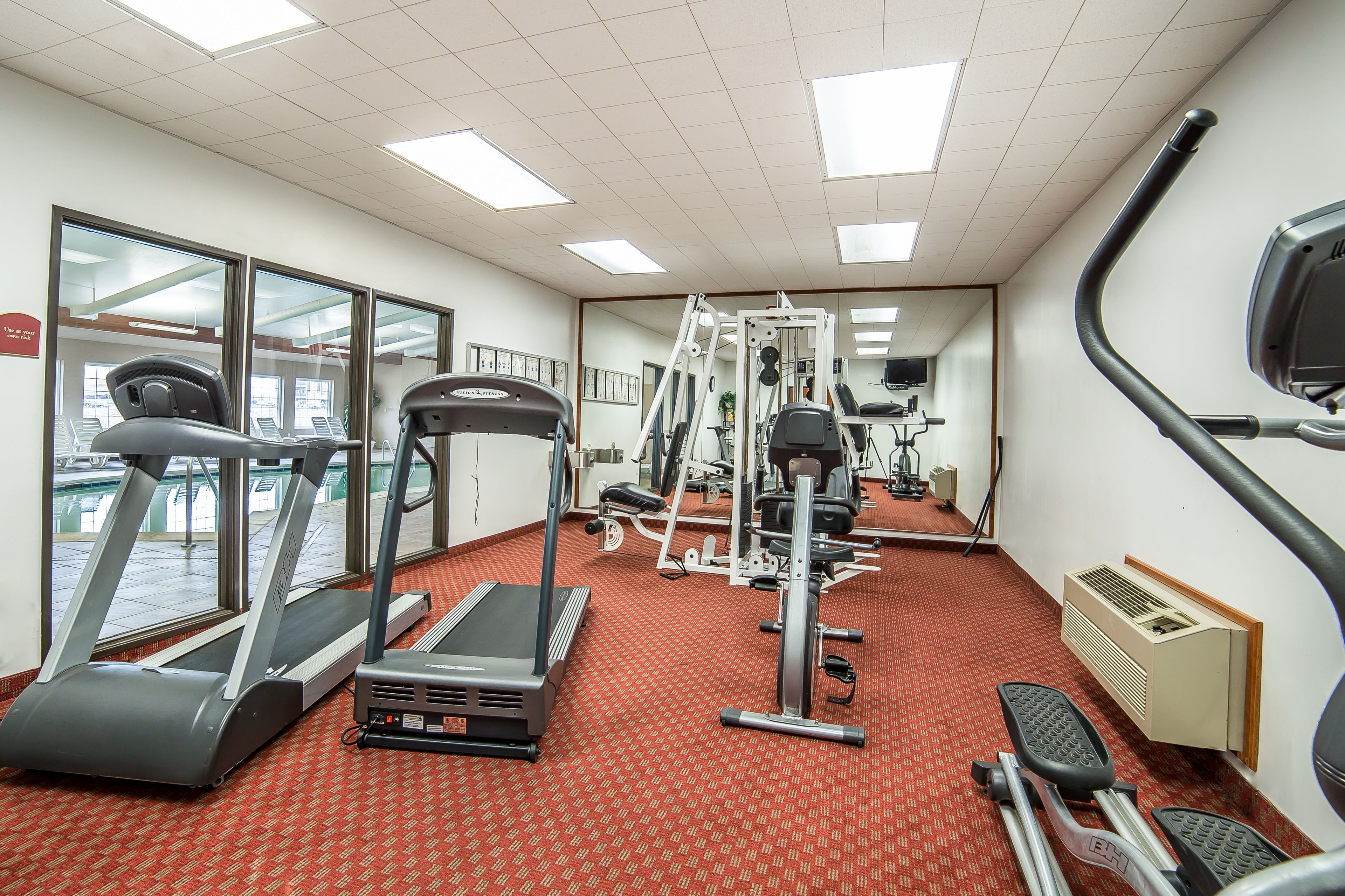 A gym with treadmills, elliptical machines, and weight equipment.