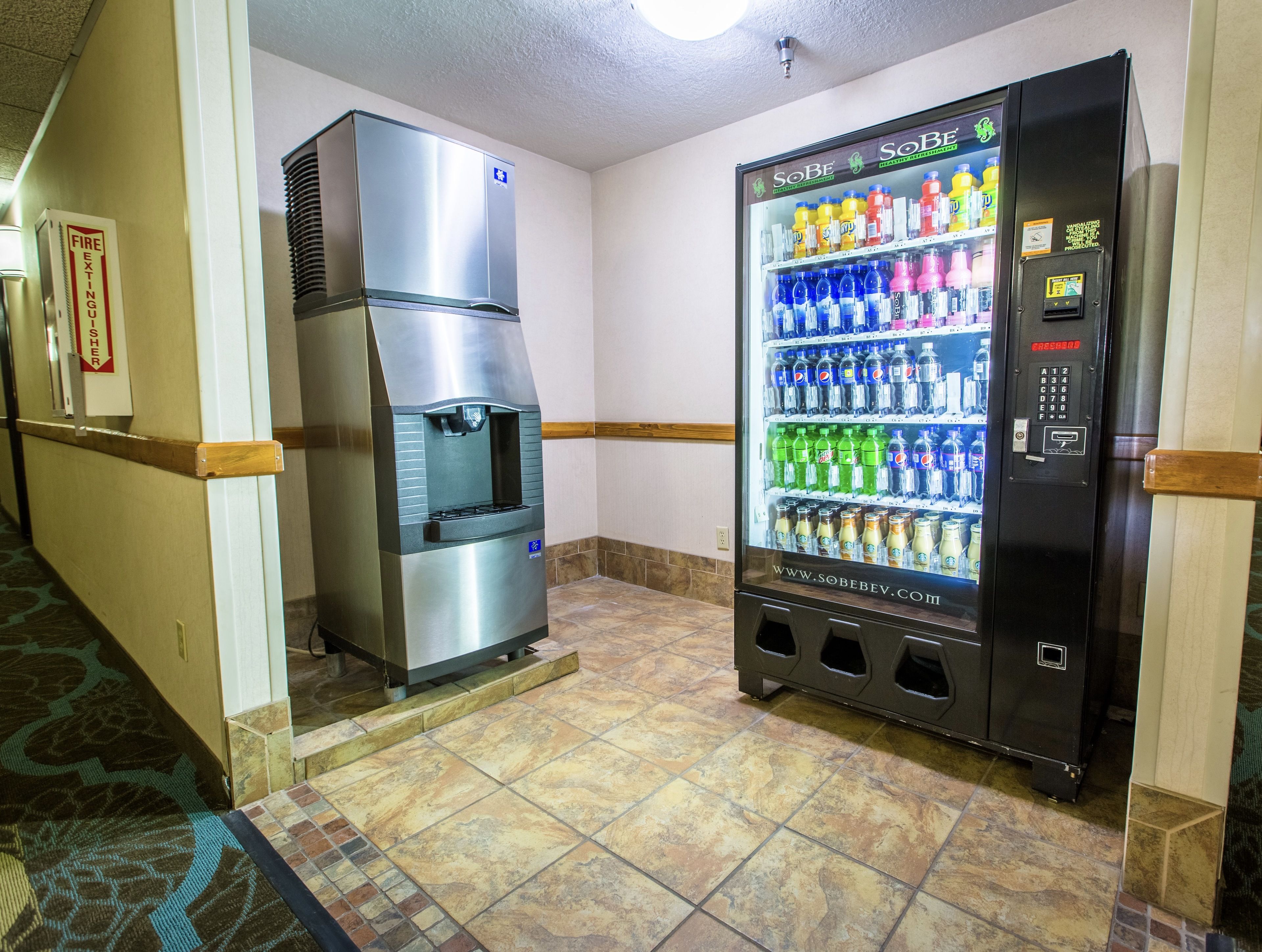 Máquina expendedora con diversas bebidas y un dispensador de agua de acero inoxidable.