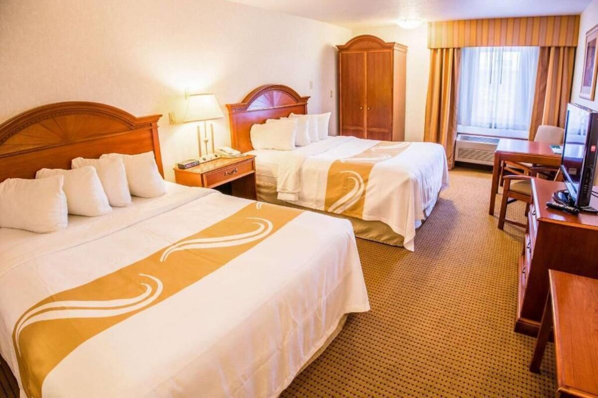 A hotel room with two beds, a desk, a television, and a wardrobe.