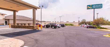 A parking lot with several cars, a covered walkway, and a sign for Quality Inn & Suites.