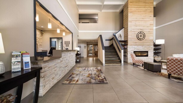 A spacious lobby with a reception desk, a fireplace, a staircase, and a seating area. - Country Inn & Suites by Radisson, Freeport, IL (Freeport)