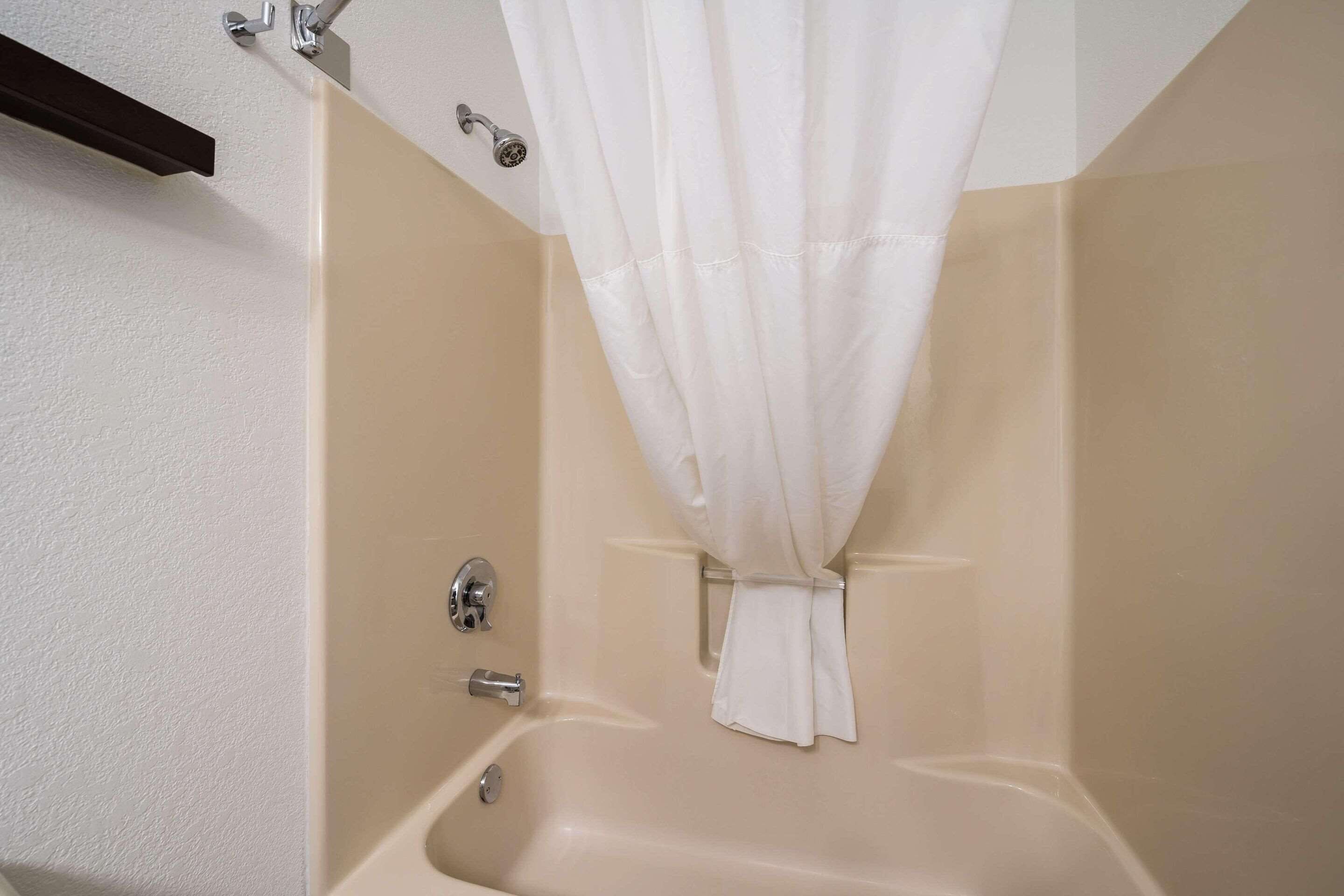 A bathroom with a bathtub, a shower curtain, and a towel rack.