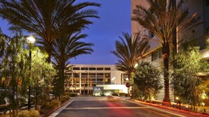 A modern hotel with a prominent 'M R' sign, surrounded by palm trees and street lamps. - Hotel MDR Marina del Rey - a DoubleTree by Hilton (Marina del Rey)