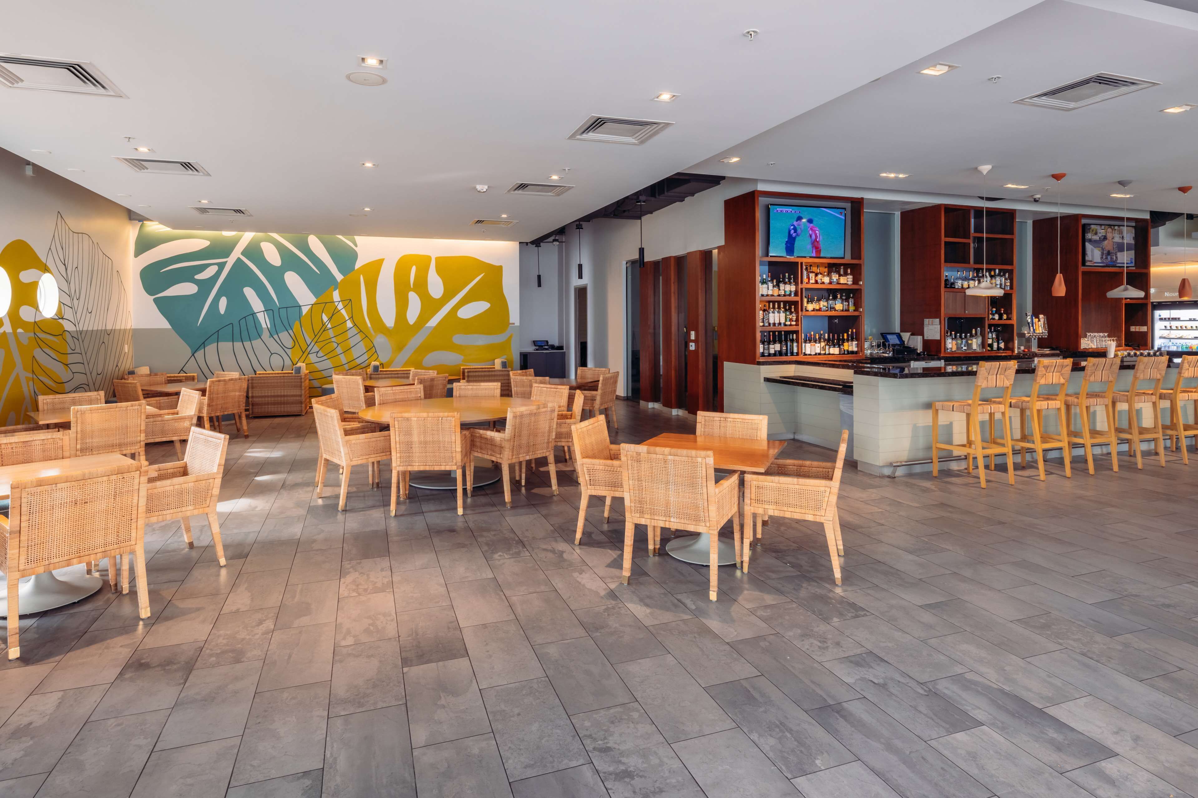 A modern bar area with wicker furniture and a large screen TV.
