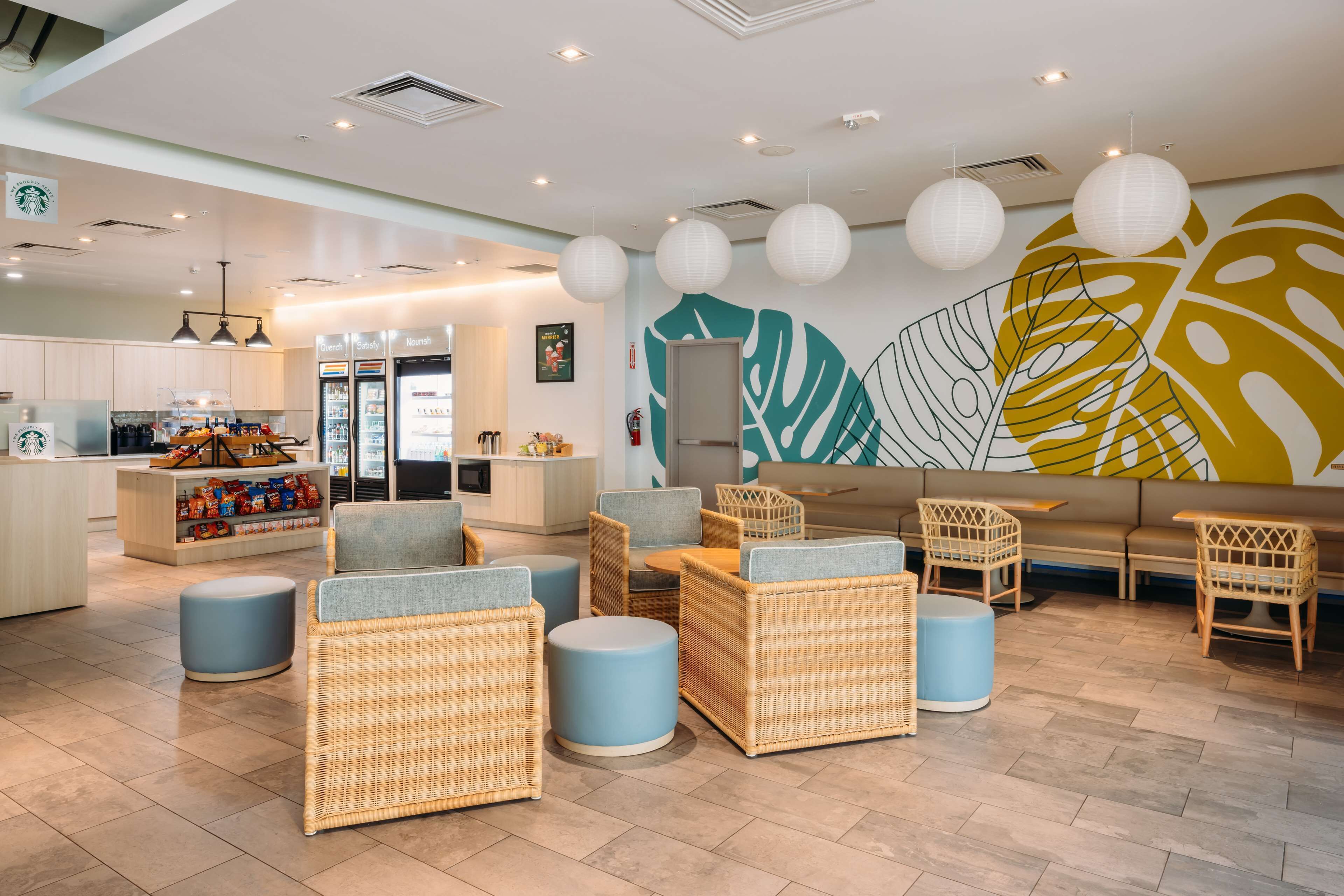 Un área lounge moderna con mobiliario de mimbre, un rincón de estar y una encimera de cocina con aperitivos.