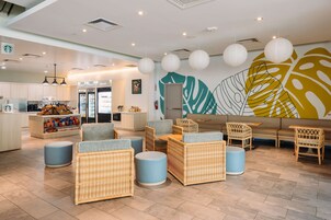 Un área lounge moderna con mobiliario de mimbre, un rincón de estar y una encimera de cocina con aperitivos.