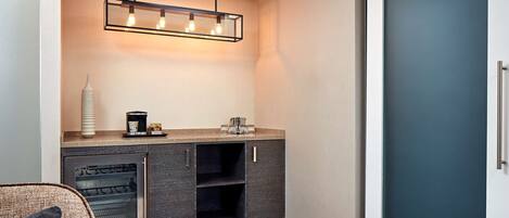Ett modernt kök med en inbyggd ugn, en kaffebryggare och en hängande lampa.