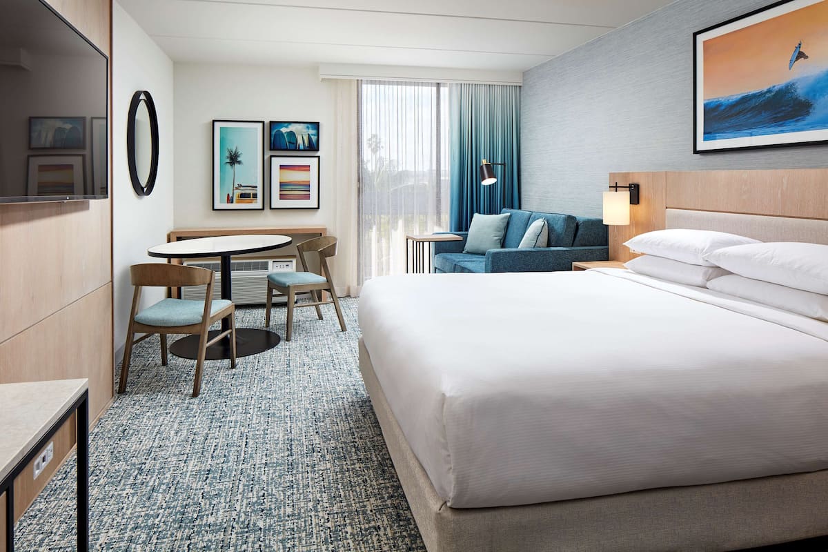 Una habitación de hotel con una cama grande, un escritorio con una silla, un sofá y una mesa de comedor.