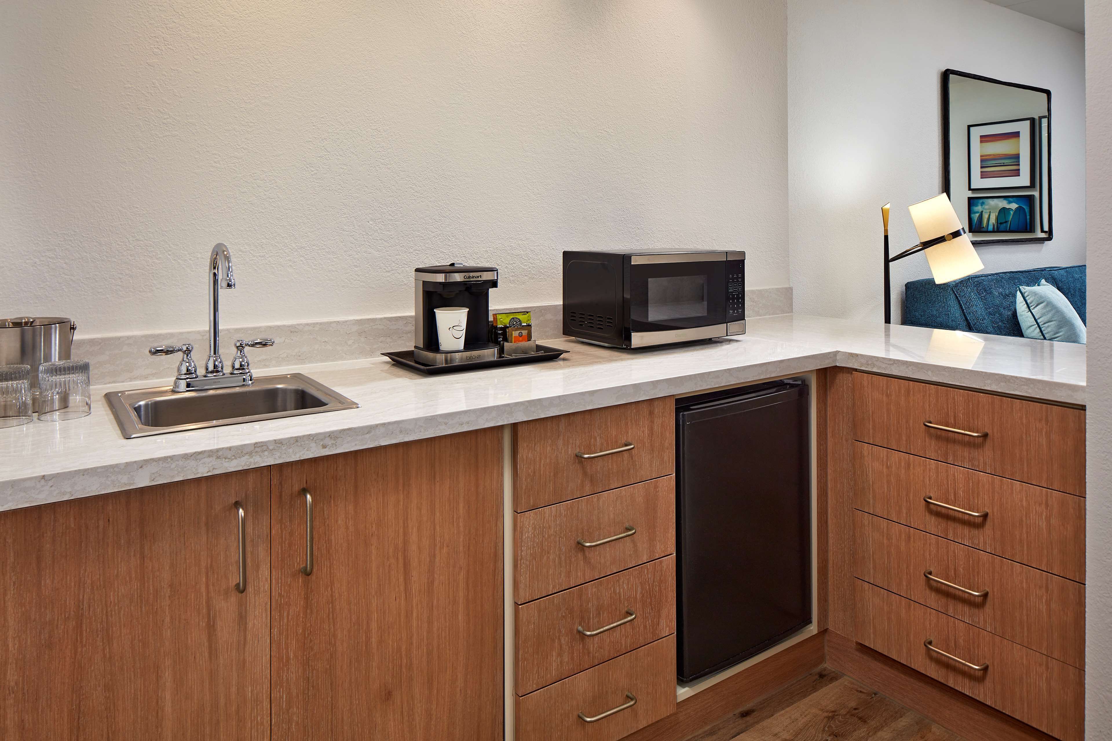 A compact kitchen with a coffee maker, microwave, sink, and dishwasher.